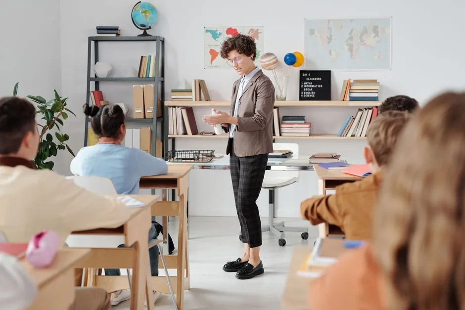 A teacher kneeling beside a rotation station of four students using tablets
